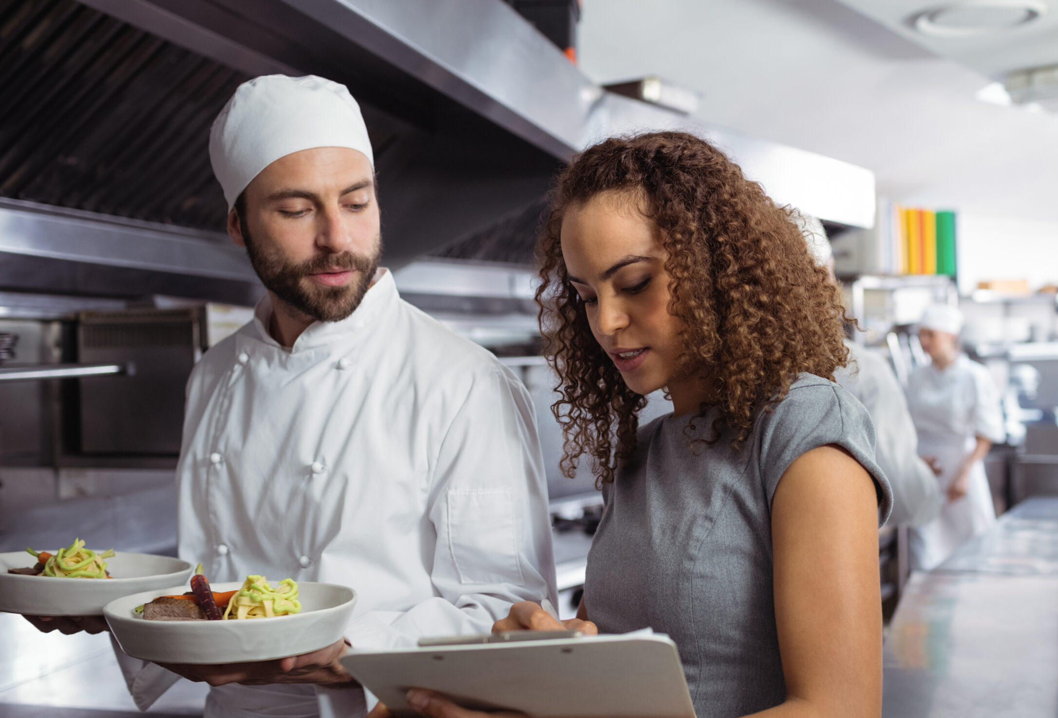 Consultant talking to chef with clipboard